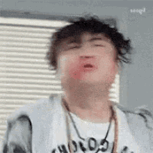 a man with a necklace around his neck is making a funny face with his mouth open .