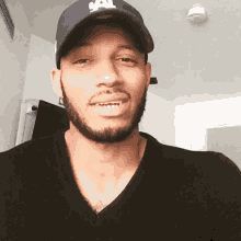a man with a beard wearing a hat and a black shirt is smiling .