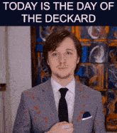 a man in a suit and tie is standing in front of a sign that says today is the day of deckard
