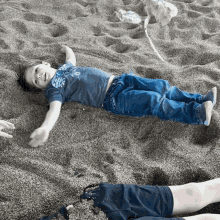 a young boy laying in the sand wearing a shirt that says abercrombie & fitch