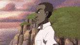 a man in a white shirt is standing on a cliff overlooking a body of water