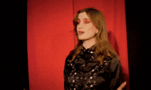 a woman in a black shirt with red lipstick on her eyes