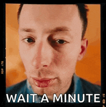 a close up of a man 's face with the words wait a minute written below him