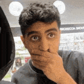 a man covering his mouth with his hand in front of a store that says home accessories