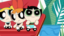 the powerpuff girls are sitting on a couch and buttercup is holding a cup of popcorn