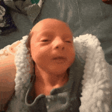 a baby is laying on a bed with a bag of popcorn behind it
