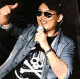 a man singing into a microphone wearing sunglasses and a skull and crossbones shirt