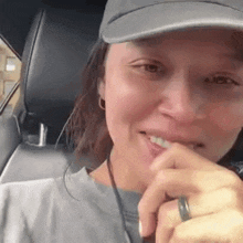 a woman is sitting in the back seat of a car wearing a hat and a ring .