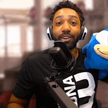 a man wearing headphones and a t-shirt that says " ona " is holding a stuffed animal
