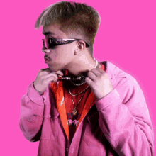 a man wearing sunglasses and a pink shirt with the word supreme on the front