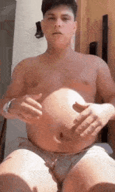 a shirtless man is holding his stomach while sitting on a bed .