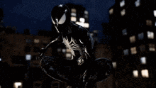 a man in a black spiderman suit is kneeling in the rain .