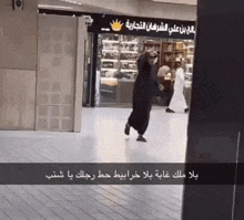 a person walking in front of a store that has arabic writing