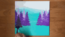 a person is painting a painting of a forest with purple trees and a blue sky .
