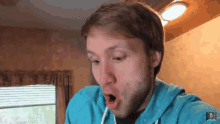 a man wearing a blue hoodie has his mouth wide open