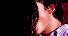 a man and a woman are kissing in a dark room