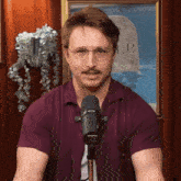 a man stands in front of a shure microphone in front of a picture of a grave