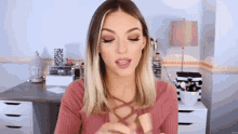 a woman in a pink shirt is sitting in front of a desk with her eyes closed .
