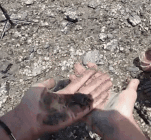 a person 's hands are covered in mud on a rocky surface