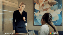 two women standing in front of a painting with the nbc logo