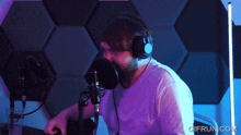 a man wearing headphones is singing into a microphone with a gifrun.com watermark