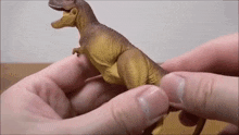 a person is holding a toy dinosaur in their hand .