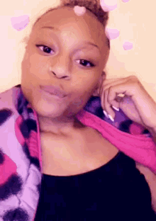 a woman wearing a purple and pink vest is making a face .
