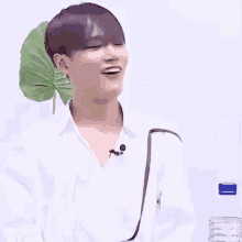 a young man in a white shirt is laughing with his mouth open and a bottle of water in the background .