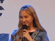 a woman is holding a microphone and smiling while wearing a headband .
