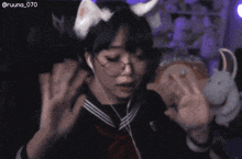a girl wearing a cat ear headband and headphones is giving the middle finger