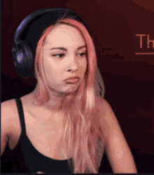 a woman with pink hair is wearing headphones