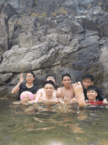 a group of young people are posing for a picture in a pool of water