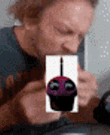 a man is drinking from a cup with a cupcake on it .