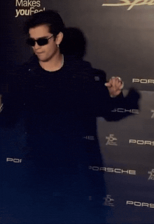 a man stands in front of a wall that says porsche