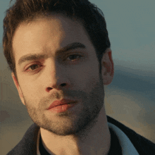 a man with a beard and a black shirt looks at the camera