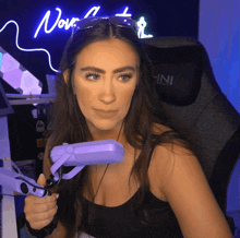 a woman sitting in front of a neon sign that says nov on it