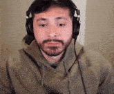 a man wearing headphones and a hoodie looks at the camera