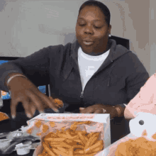 a woman takes a piece of chicken from a box