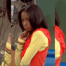 a girl wearing a yellow shirt and a red top has a ring on her finger