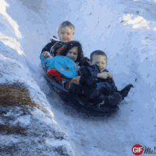 a woman and two children are sledding down a snow covered hill with a gif me logo in the corner