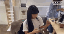 a girl with long black hair is sitting at a table with a sign that says secret number on it