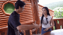a man and a woman shake hands in front of a wooden building
