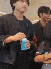 a man in a black jacket is holding a can of soda .