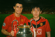 a man in a manchester united shirt holds a trophy