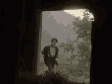 a man is walking through a doorway in a field .