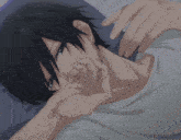 a man with black hair is laying on a bed with his hand on his face