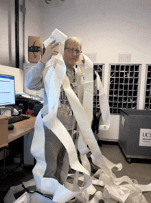 a man is wrapped in toilet paper in front of a ucs recycling bin