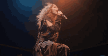 a woman is singing into a microphone on stage