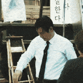 a man in a white shirt and black tie is looking down