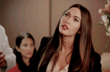 a woman with long hair is wearing a black jacket and a pink top